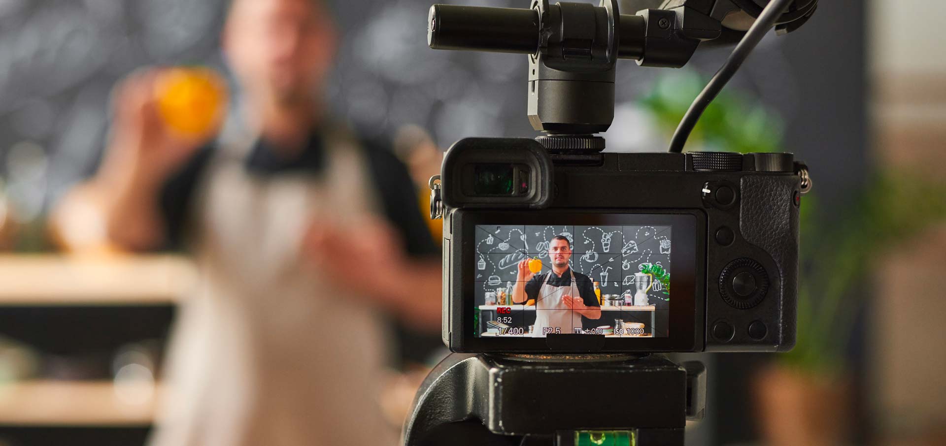 Close up view of video camera filming a chef's demonstration in the distance